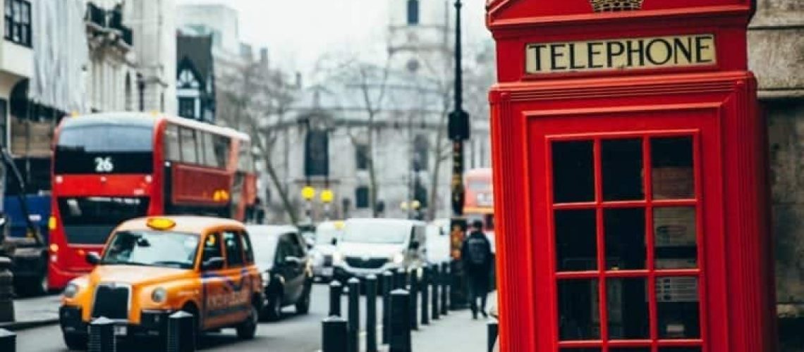 A shot of the telephone booth in red with taxi on the road in london